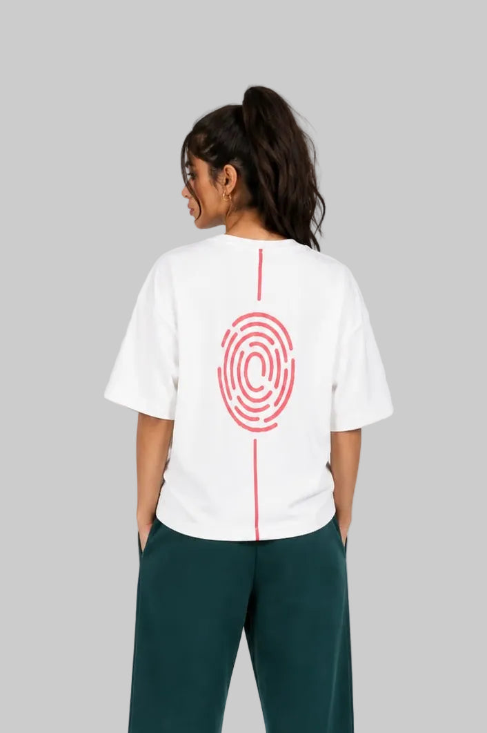 A model shown from the back wearing a white t-shirt with a red spiral graphic and a vertical red line down the center, paired with dark green sweatpants and white sneakers, against a light gray studio background.